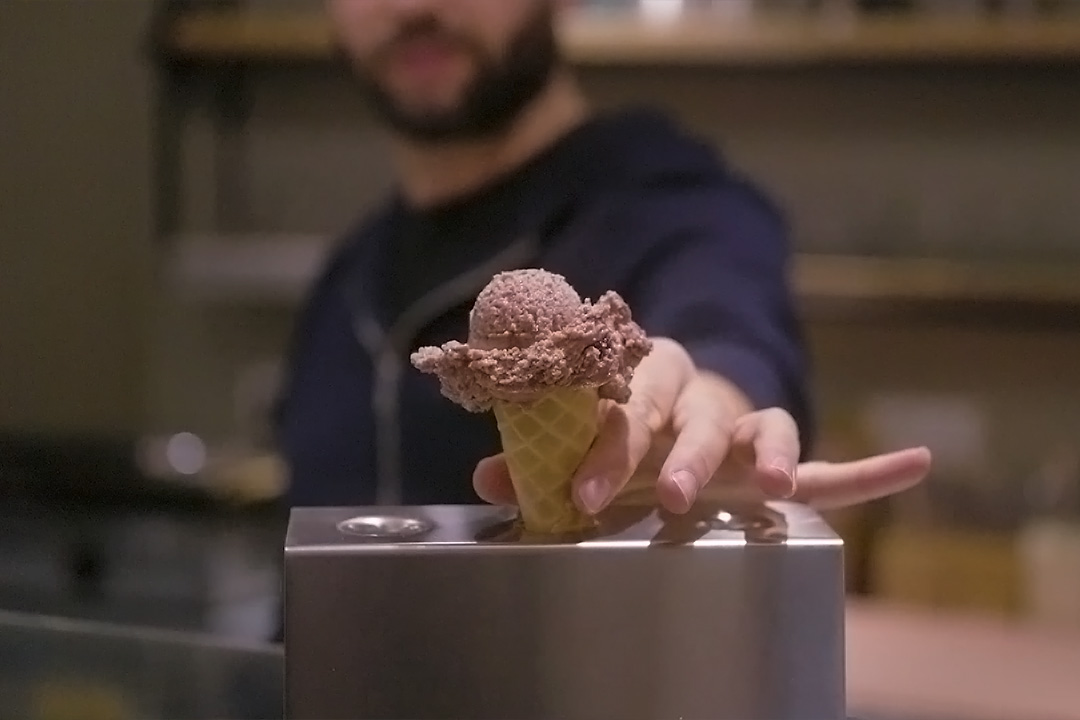 Eine Kugel Eis in einer Eistüte, die von einem Mann, eine Halterung gestellt wird.