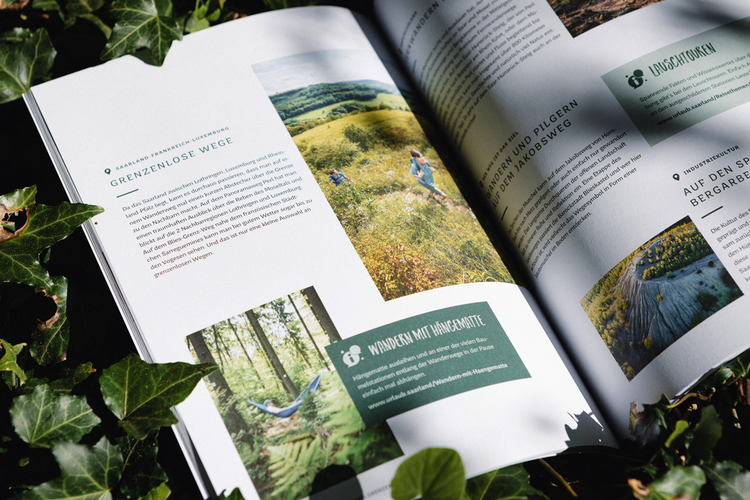 Bild des Heimat Magazins der Tourismus Zentrale Saarland, welches an einen Baumstamm im Wald lehnt. Es zeigt 2 Innenseiten.